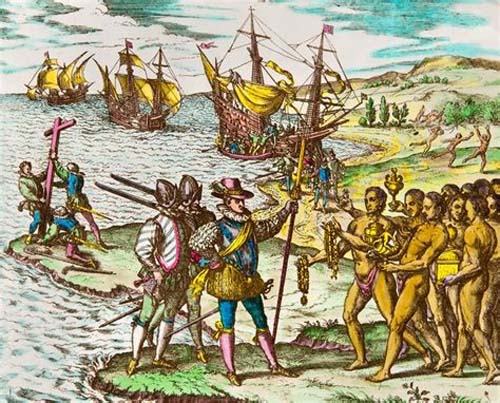 Exploradores con vestimenta histórica europea interactúan con un grupo de personas indígenas en una costa donde hay barcos de vela anclados y otras personas observando desde la orilla.

Descripción generada con IA